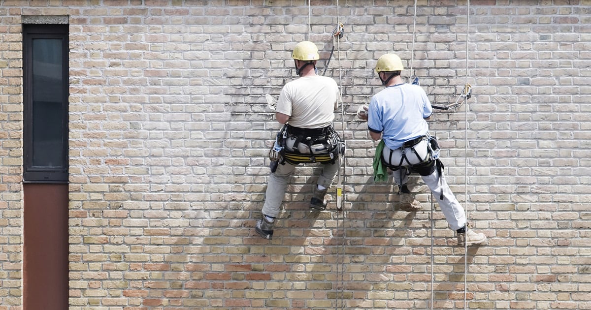 Two workers renovating the facade of an apartment building