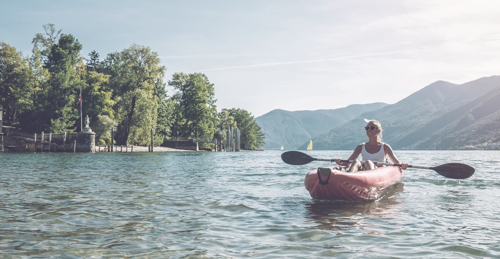 A woman kayaking on a lake in a picturesque mountain setting