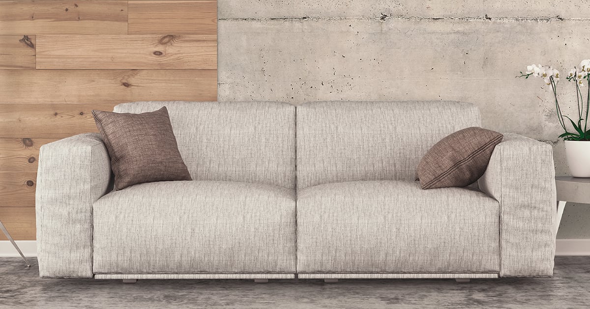 Ein Sofa steht vor einer Wand aus Holz und Beton. 