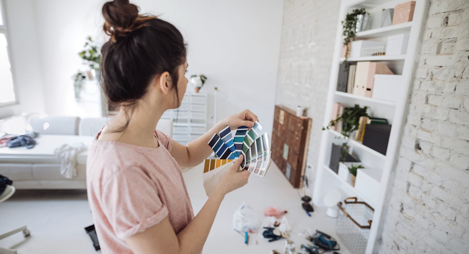 Eine Frau wählt die passende Wandfarbe für ihr neues Zuhause aus, das sie über eine Zwischenfinanzierung erwerben konnte.